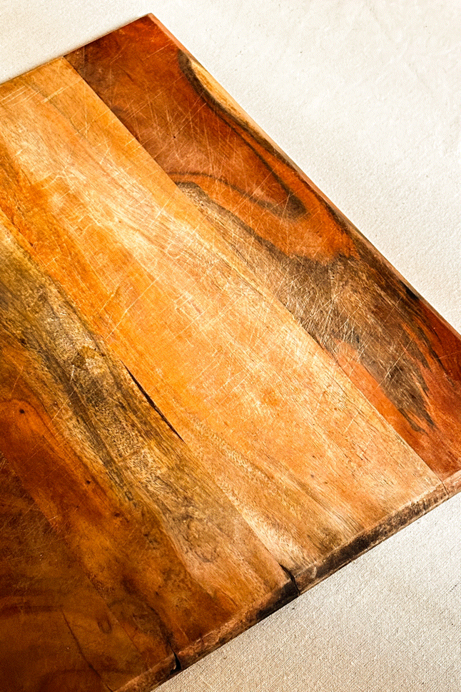 Wooden cutting board surface with natural grain patterns and warm tones.