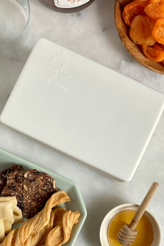 CapaBunga Cheese Vault on a marble countertop with snacks and honey, designed to preserve cheese freshness.