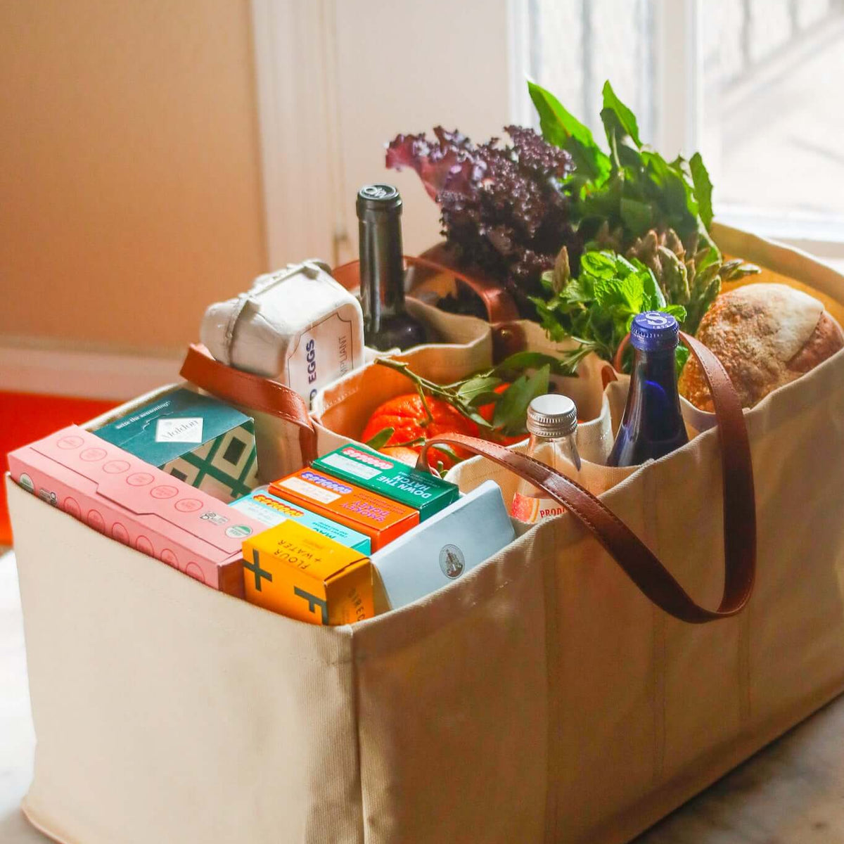 Eco-friendly canvas grocery tote filled with fresh produce, eggs, and beverages on a countertop.