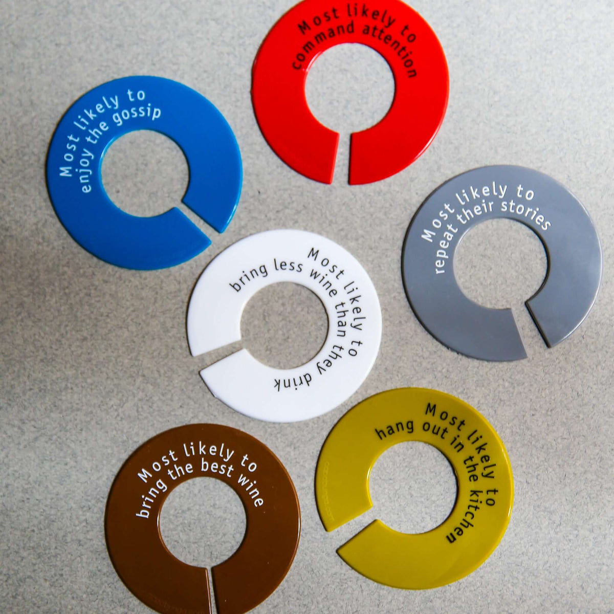 Colorful silicone wine glass identifiers with humorous labels for parties and events.