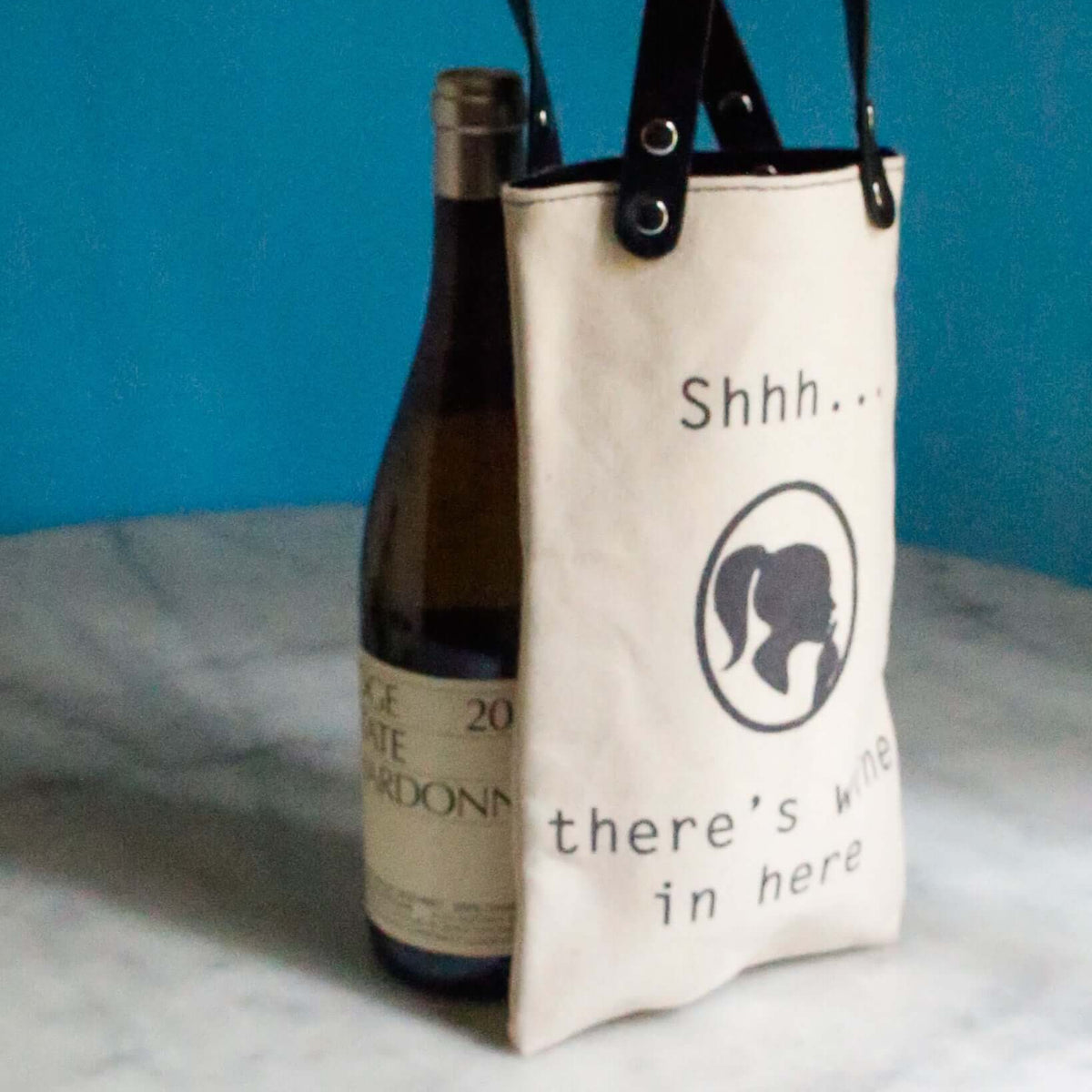 Shh There Is Wine Canvas Wine Tote with a bottle of Chardonnay, featuring black vegan leather handles.