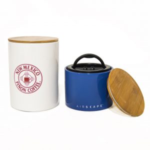 Photo of a blue canister with lid and a larger white canister with the words New Mexico Pinon Coffee written in red.
