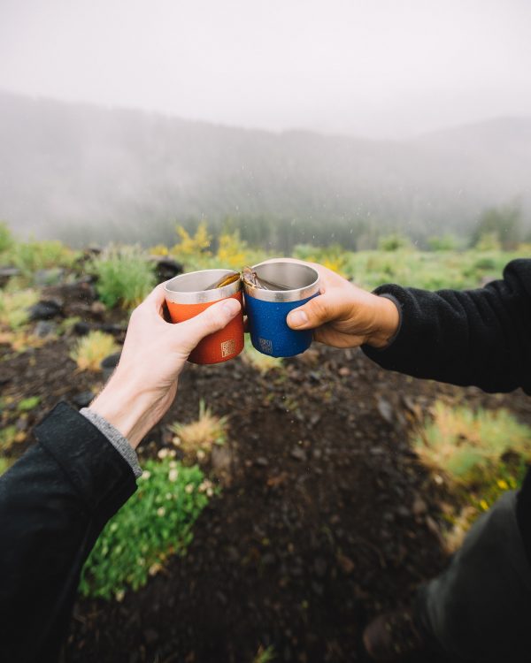 Photo of two hands each holding a BruTrek Camp Cup with coffee in them, giving each other a "Cheers!"