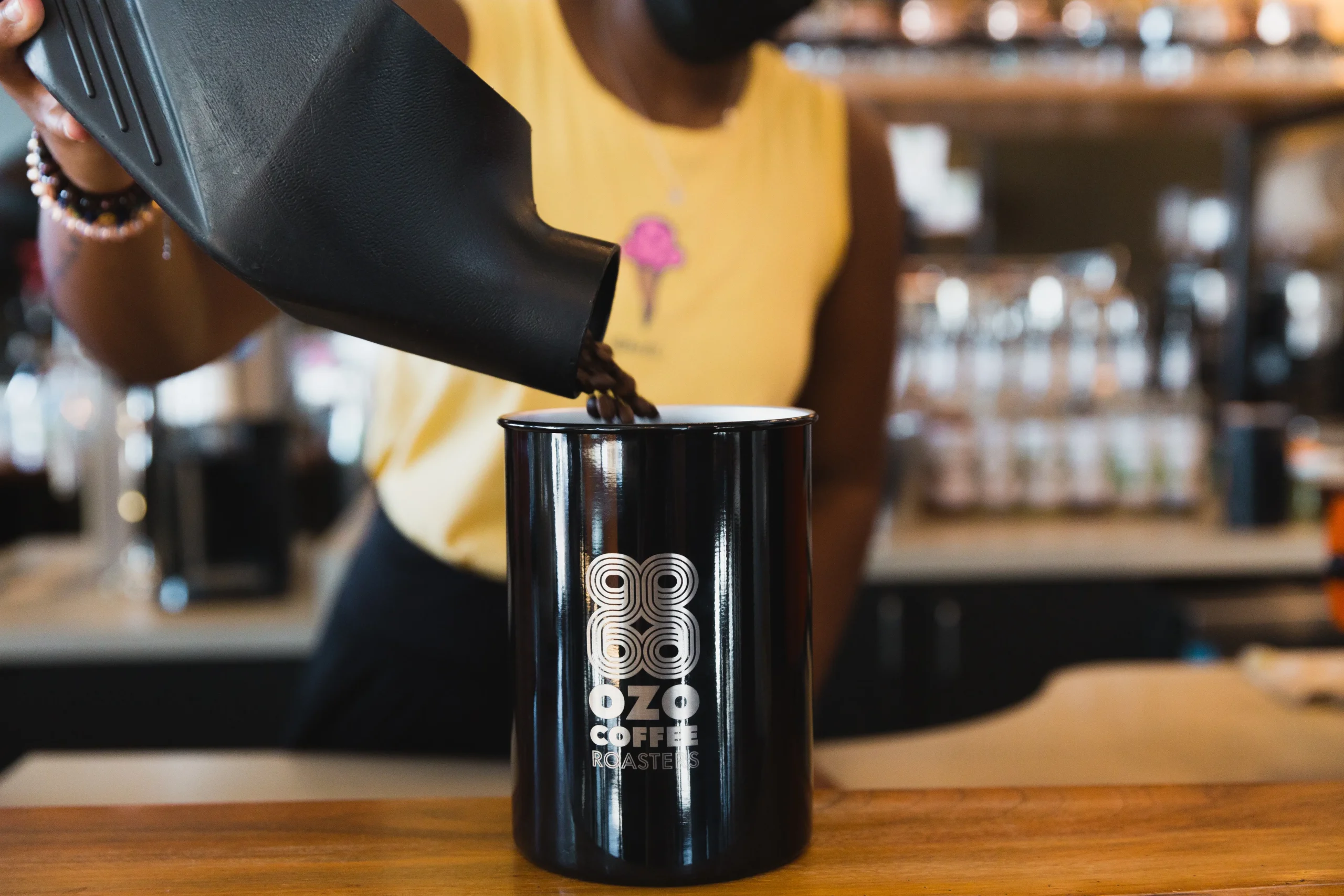 Barista carefully pouring coffee beans into Custom OZO Coffee Airscape Canister