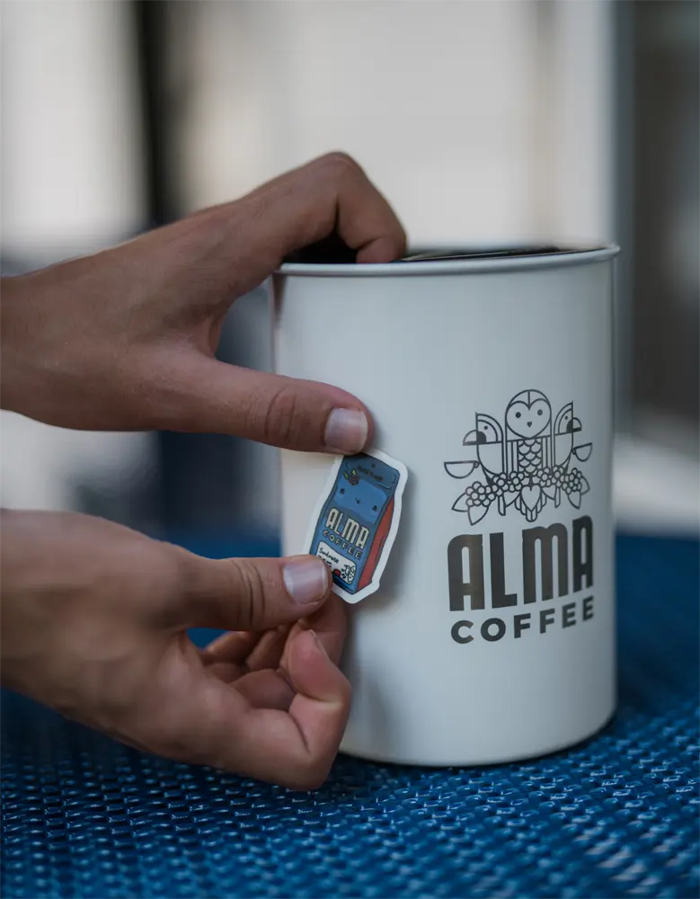 person putting sticker on alma coffee custom airscape container