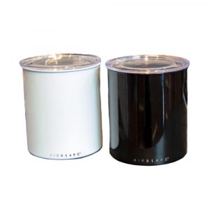 Photo of two, one kilo canisters, one white and one black, both have lids on them.