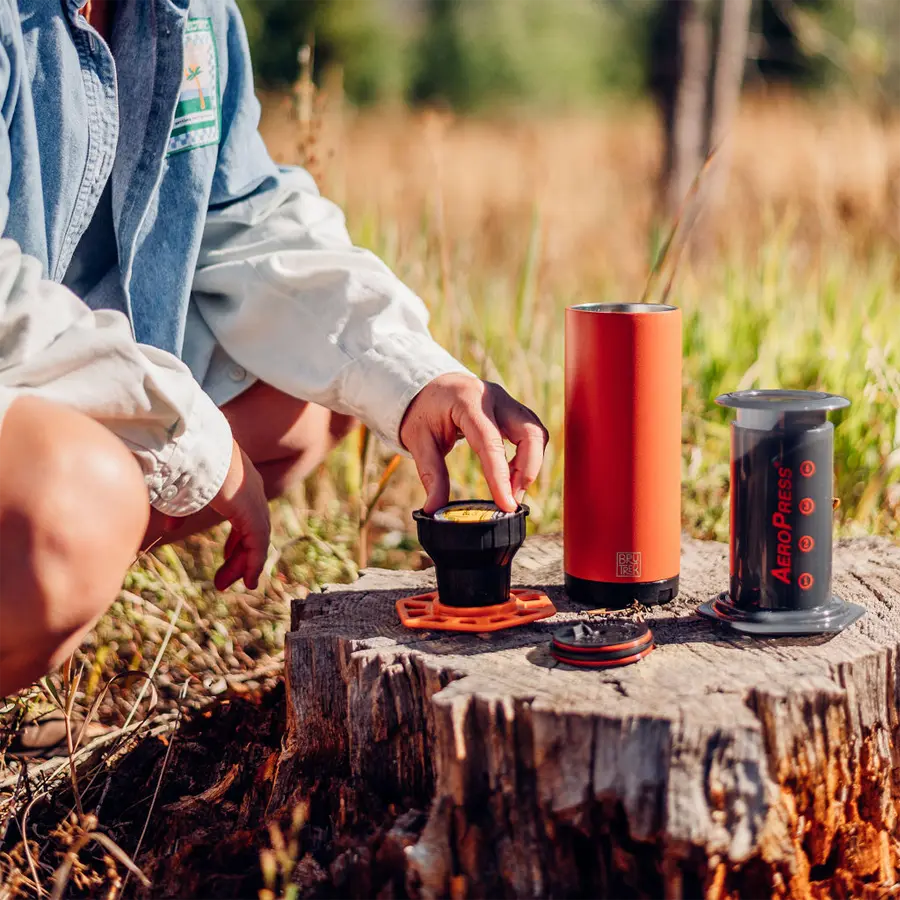 person making kcup coffee with the trestle on a tree stump