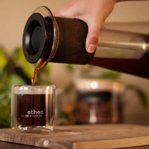 person pouring coffee into glass cup out of borosilicate french press