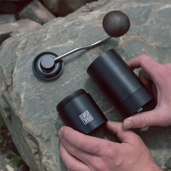 person laying coffee grinder parts onto rock