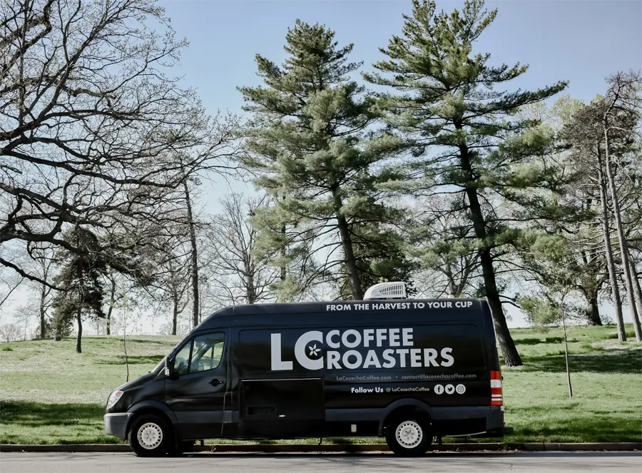 A custom La Cosecha Coffee Van in a grass field
